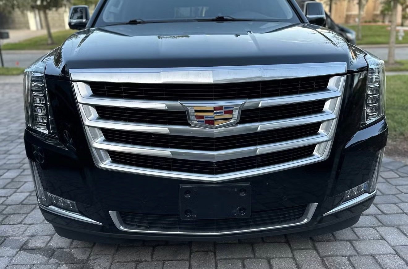 Front grille of a black Cadillac vehicle with a license plate holder.