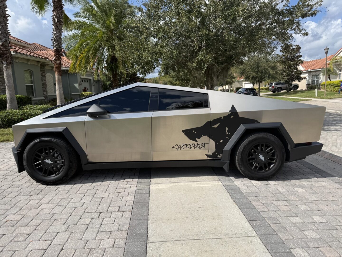 Futuristic Tesla Cybertruck with a large black shark decal on the side.