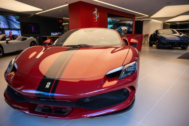 A red Ferrari with black racing stripes in a showroom.